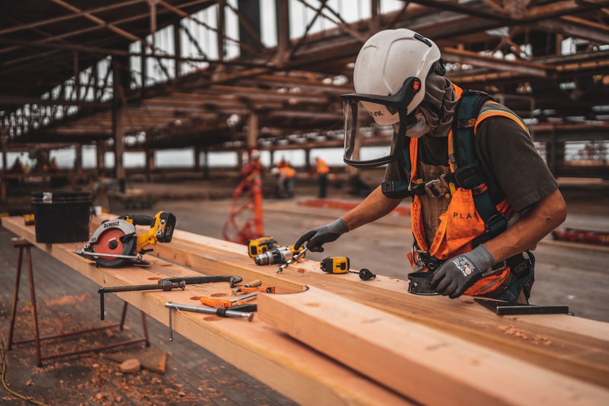 Reserva Construction crew member in a hard hat and safety gear operating power tools on wooden framing
