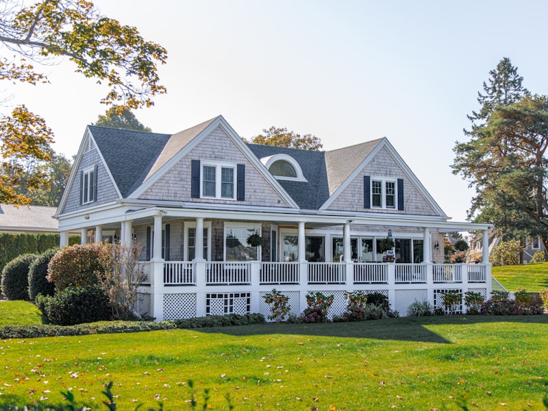 Well-maintained white two-story home with wrap-around porch and manicured lawn